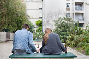 Couple sitting on bench with a beer talking about whether they need drug detox programs